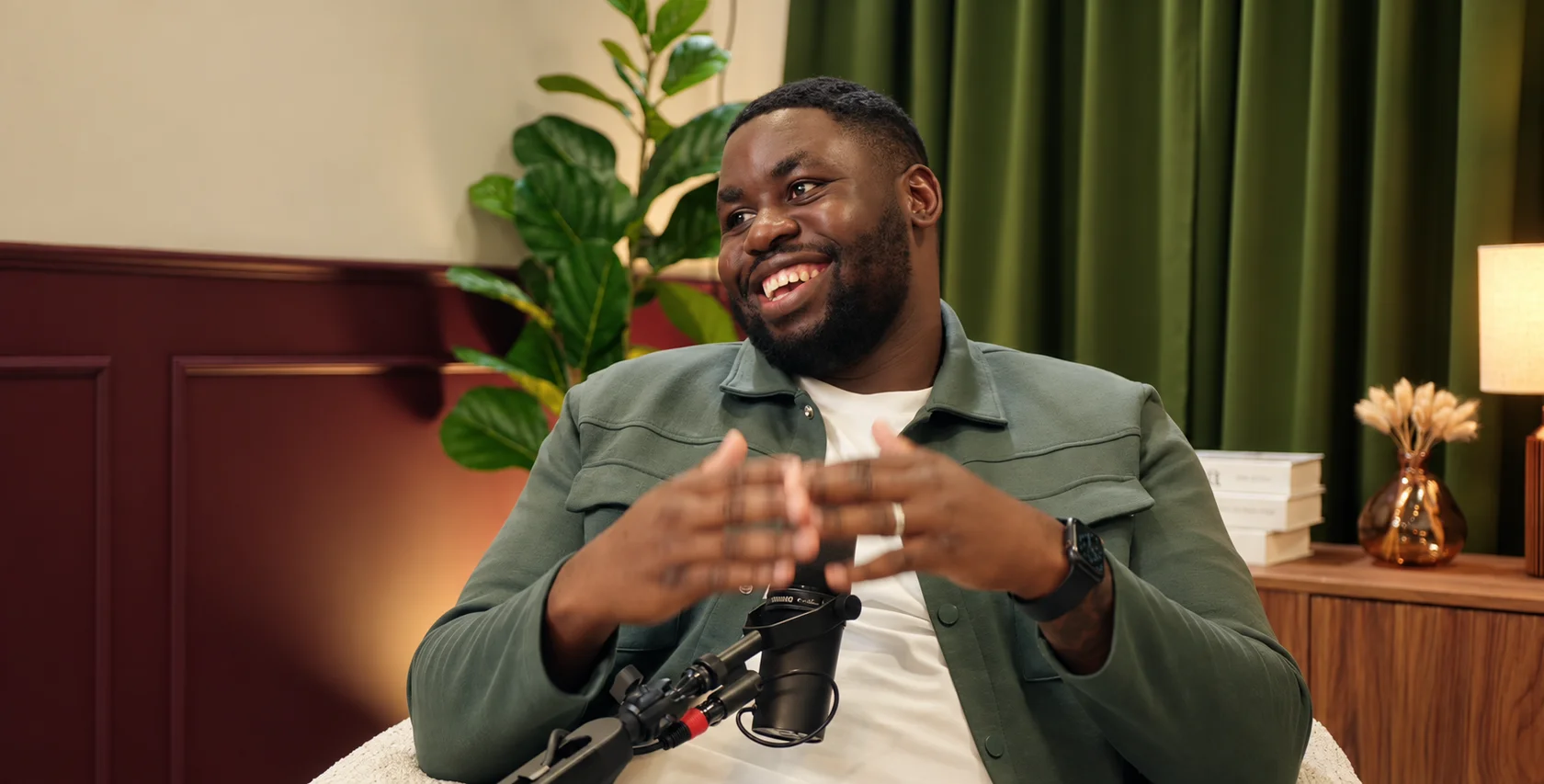 A smiling guest in a green jacket during a studio recording
